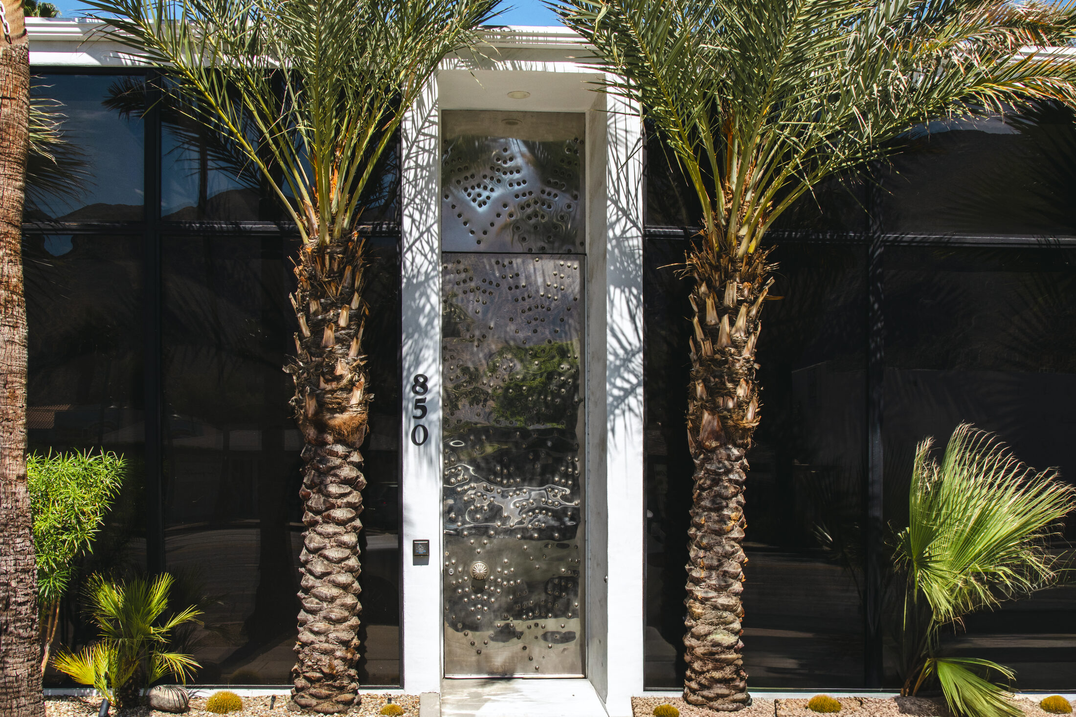 850 N Palm Canyon Drive — the iron entry door framed by twin palms
